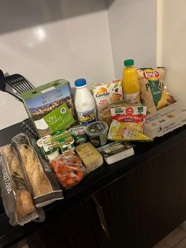 a kitchen worktop with groceries on it including milk, eggs, bread and cheese