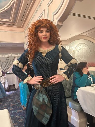 Merida posing with her hands on her hips inside the restaurant