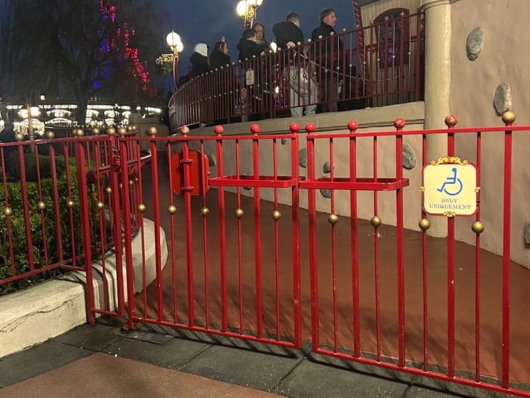 Photo of the outside of the ride accessible entrance with a red fence with a wheelchair symbol sign