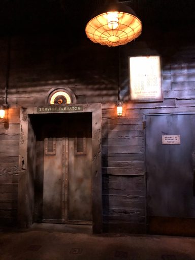 A brown wall and brown elevator door with a light above