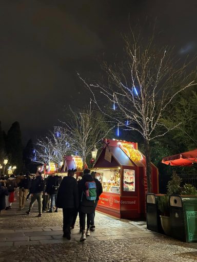 Image of some bare trees with some lights and some wooden chalets style food huts