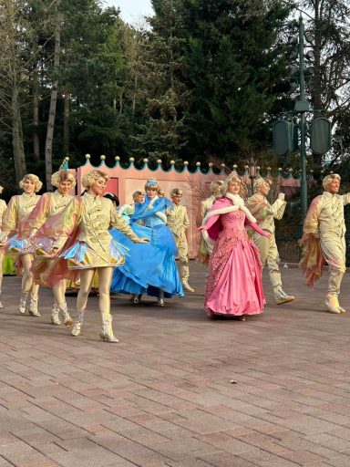 Aurora and cinderella are seen being escorted by people in gold costumes