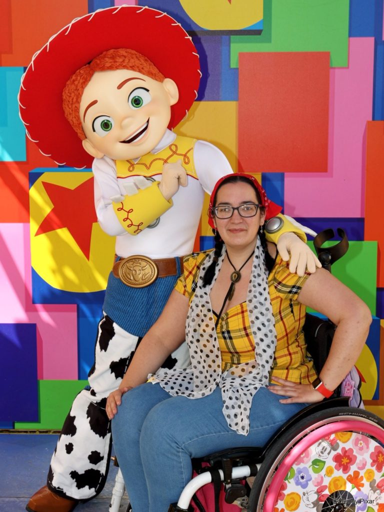 An image of a brunette wheelchair user wearing a woody inspired outfit seated next to Jessie from Toy Story