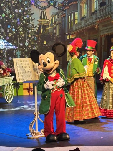 Mickey in a christmas red and green outfit on stage