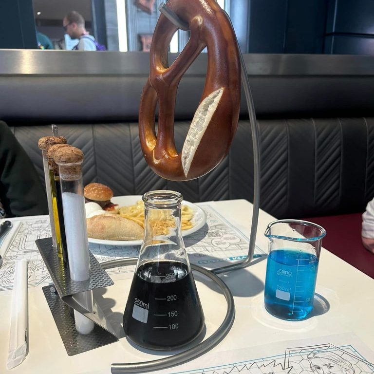 Our table at pyms kitchen with a large pretzel hanging from a stand, slt and oil in test tubes, coke served in a conical flask and blue wine served in a science beaker