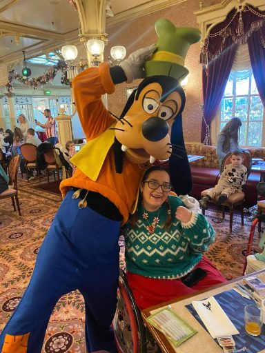 Goofy standing next to me and leaning in for a hug, i'm seated in my chair