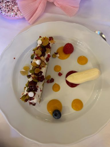 Image of a finger of dessert with nuts n top and a small white chocolate shoe