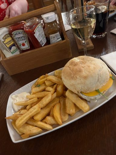 a white plate with a burger in a white bun and some chips