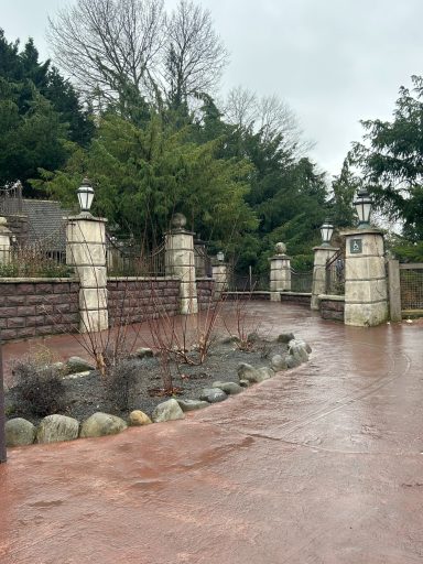 A red paved path with stone a iron fences