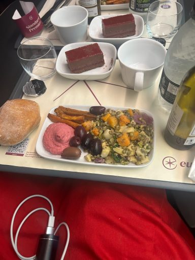 Image of some food items on a tray inclusing a cup, bread roll, grain salad and a chocolate tart