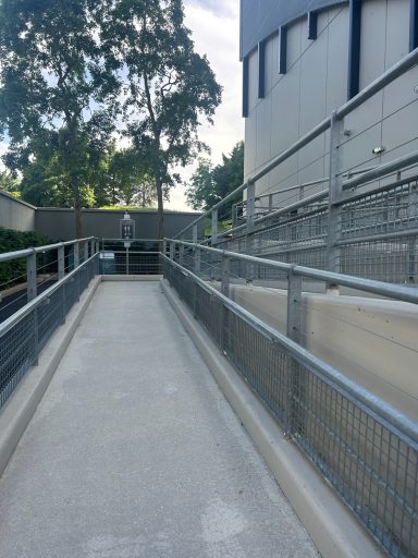 A grey concrete ramp with handrails either side