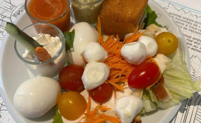 Plate of food from Pyms Kitchen, including hard boiled egg, grated carrot, mozerella balls, cherry tomatoes, lettuce and mayonaise, plus some hummus and breadsticks in a shot glass